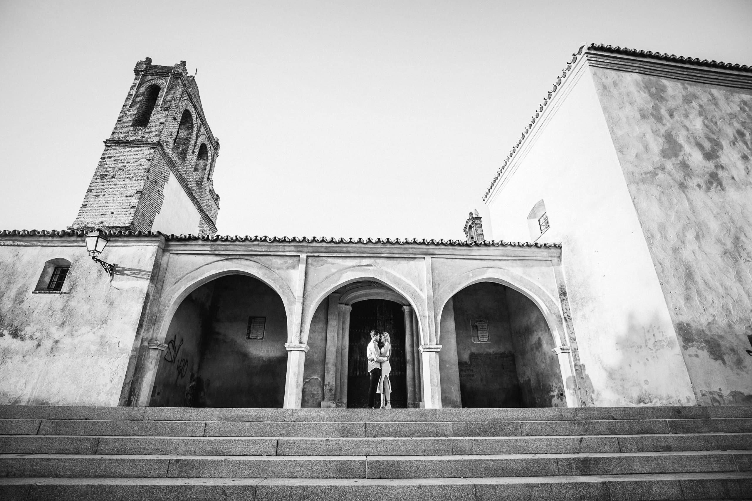 La ermita del pueblo vista desde las escaleras, con los dos diminutos bajo el arco de la entrada, en blanco y negro