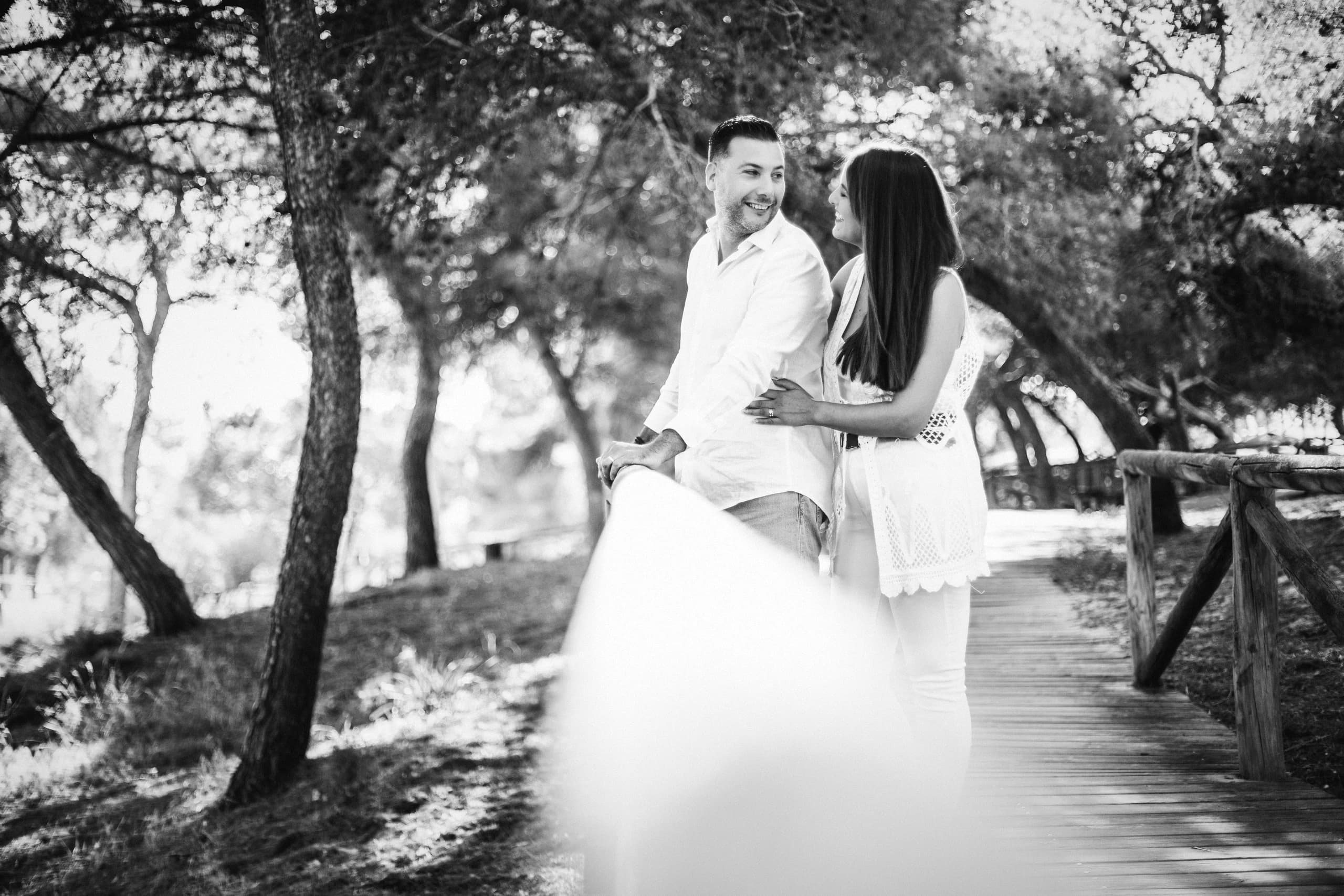 Abrazo bajo los pinos junto a la pasarela, en blanco y negro