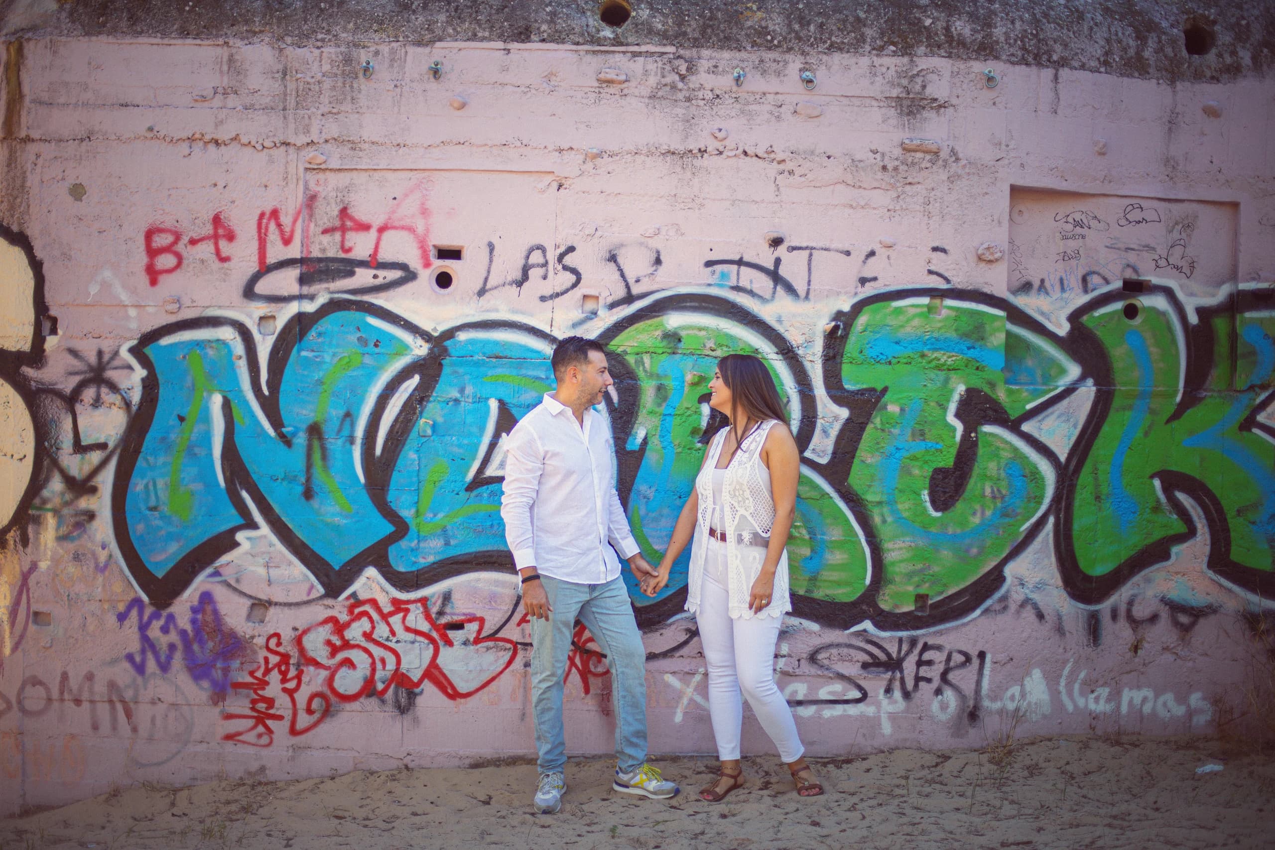 Los dos frente a un muro de grafitis de colores