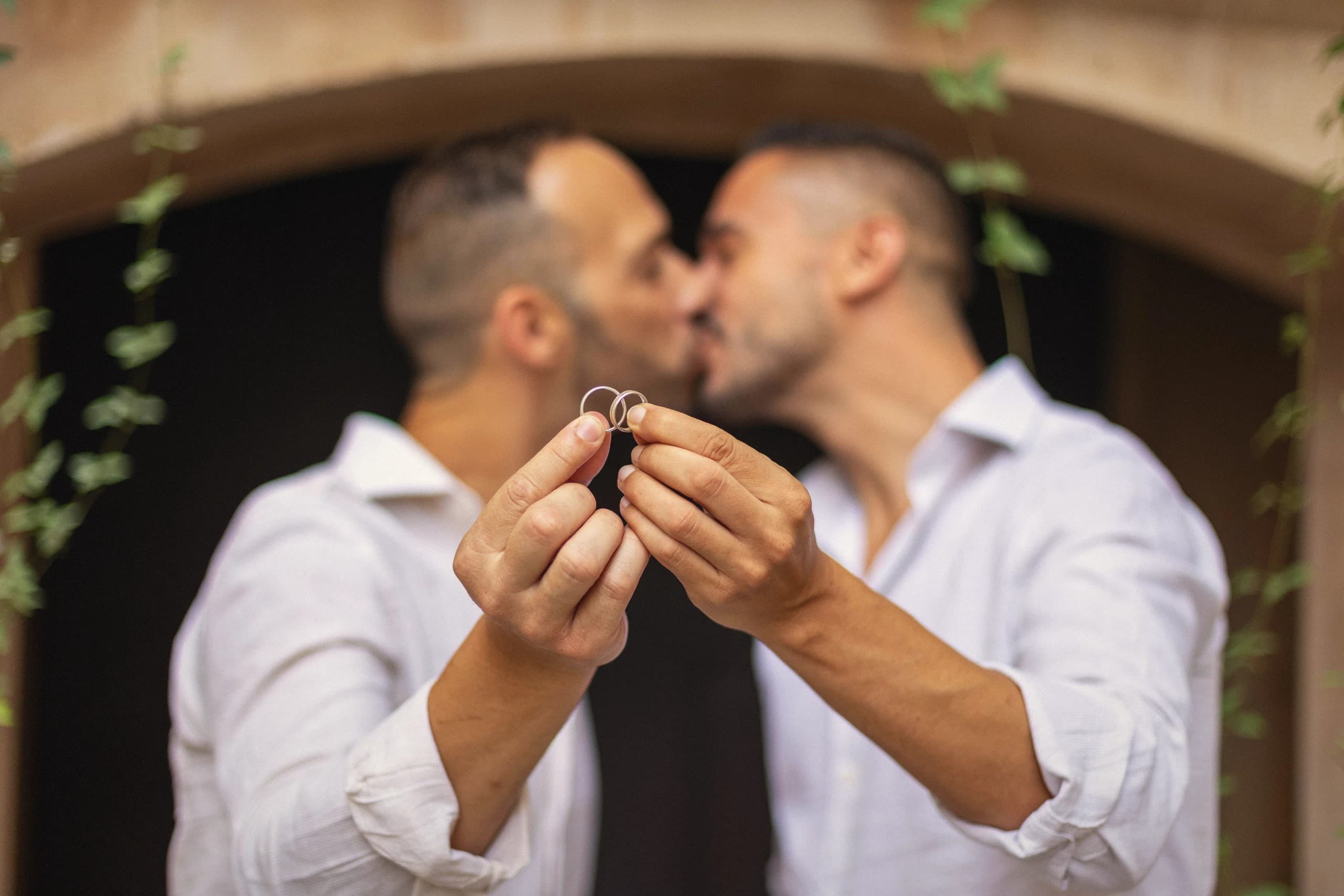 Beso con los anillos en la mano bajo el arco de piedra