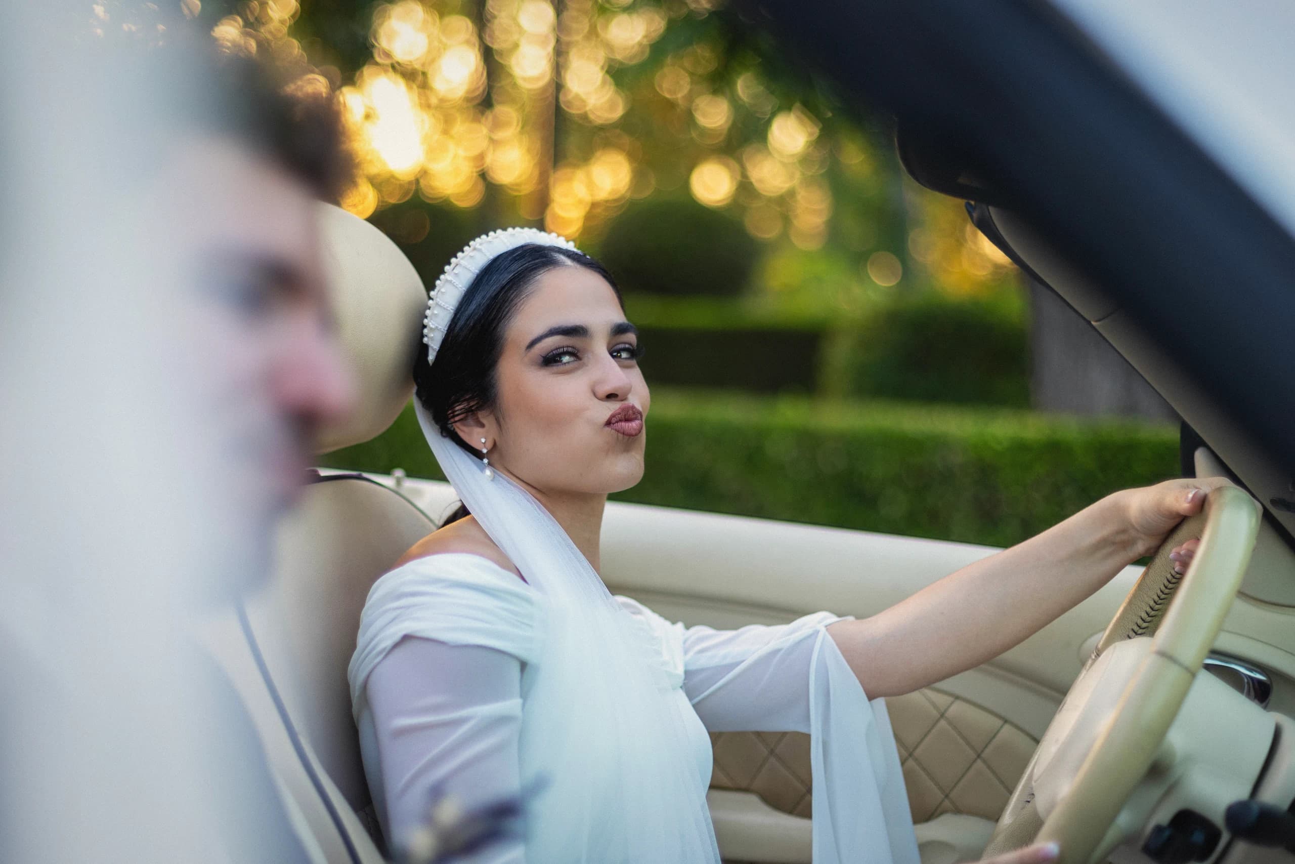 La novia al volante del coche clásico, a la luz del atardecer