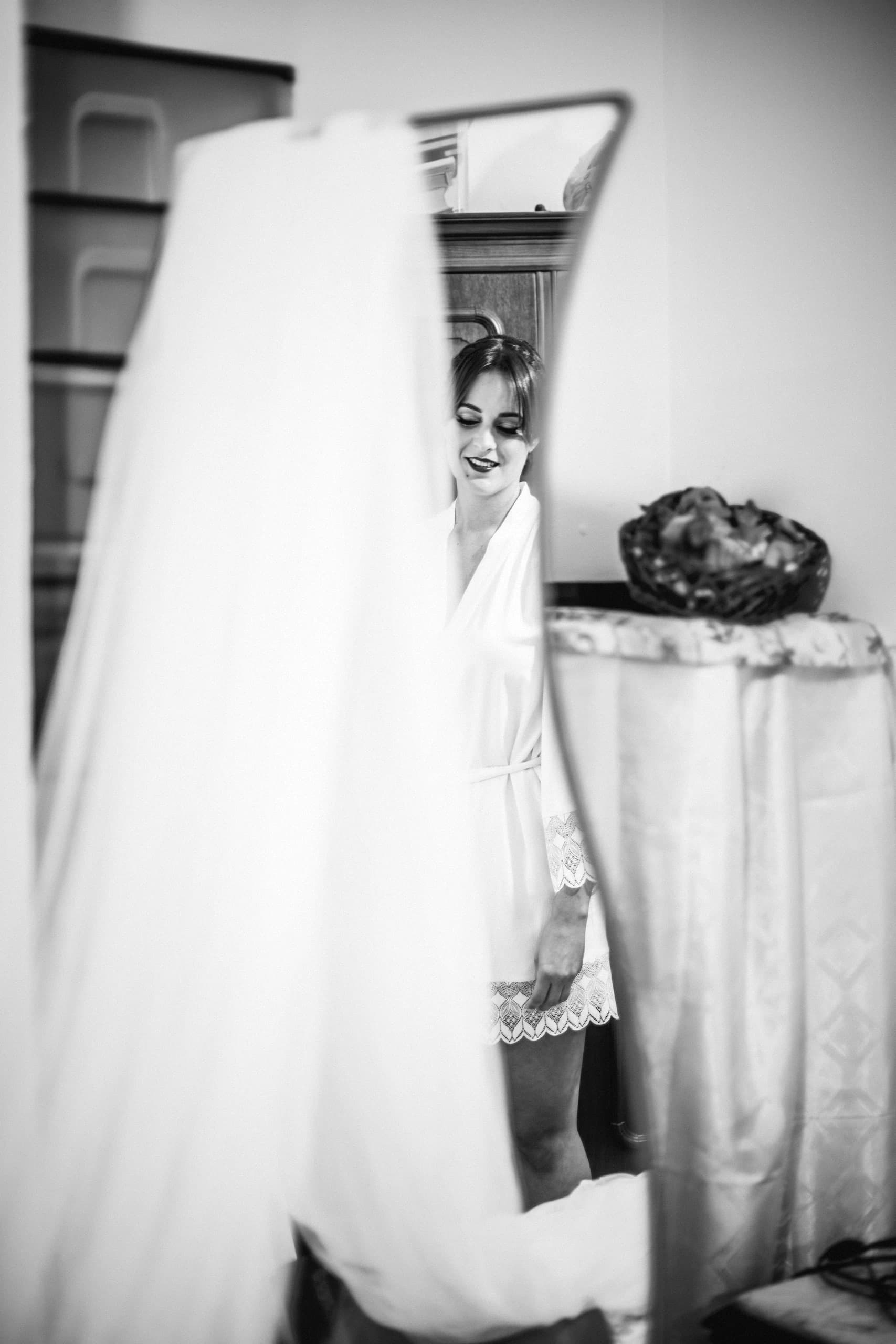 La novia reflejada en el espejo con el vestido, en blanco y negro