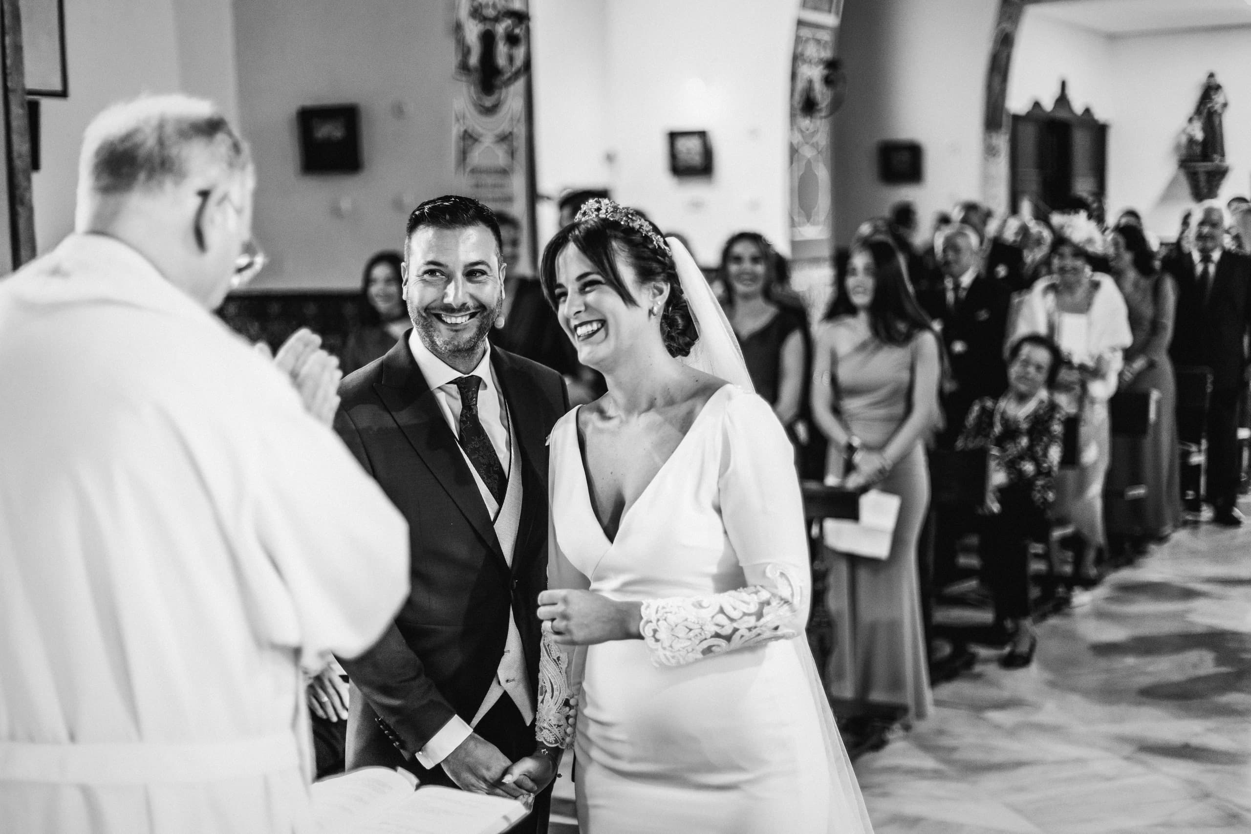 Los novios riendo ante el sacerdote, en blanco y negro