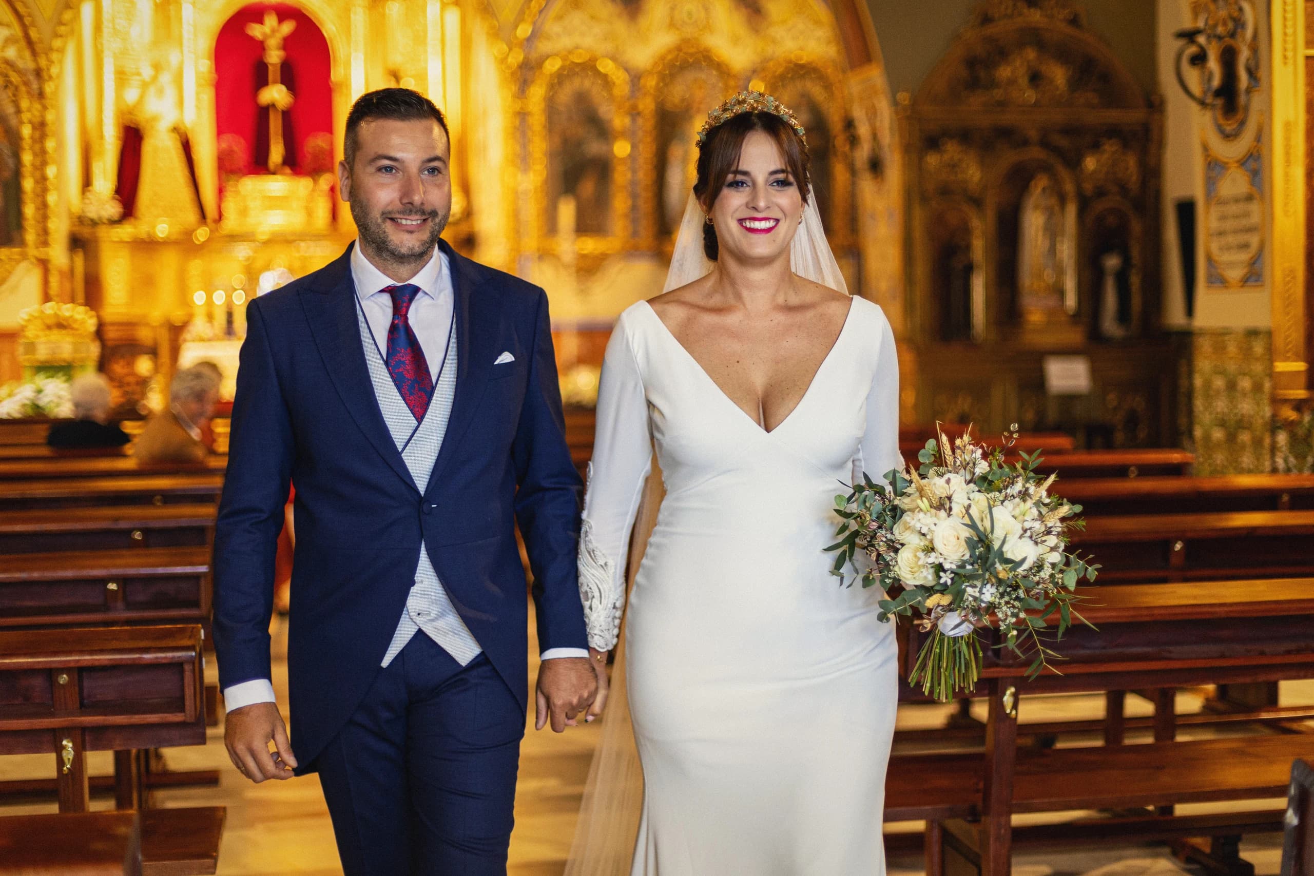 Los novios saliendo por el pasillo de la iglesia dorada