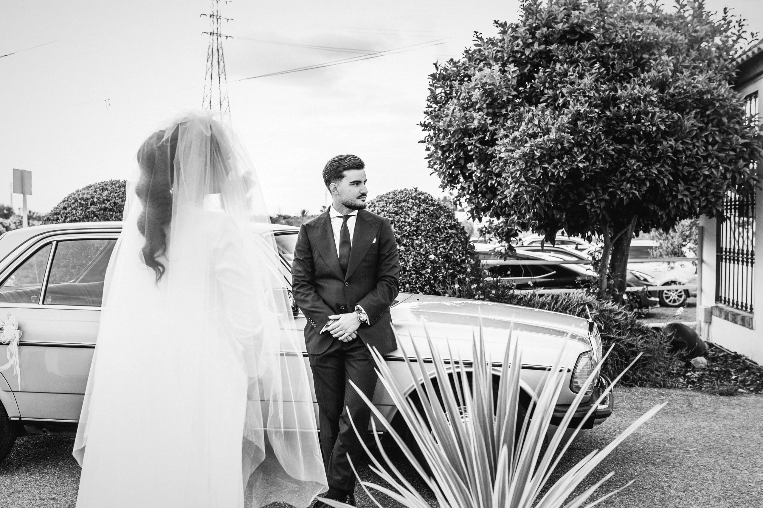 El novio esperando junto a un coche clásico mientras llega la novia