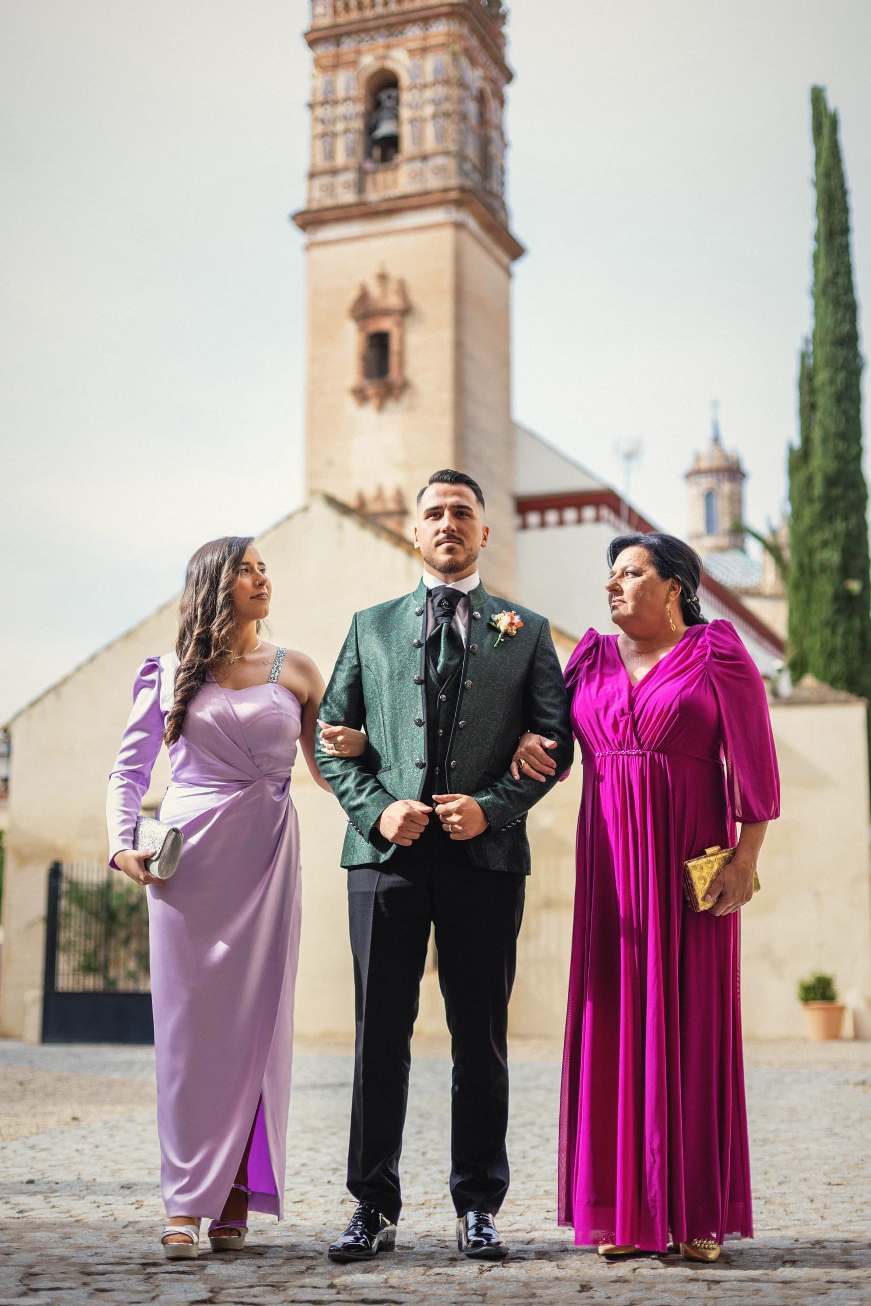 El novio con su madre y su hermana ante la torre de la iglesia