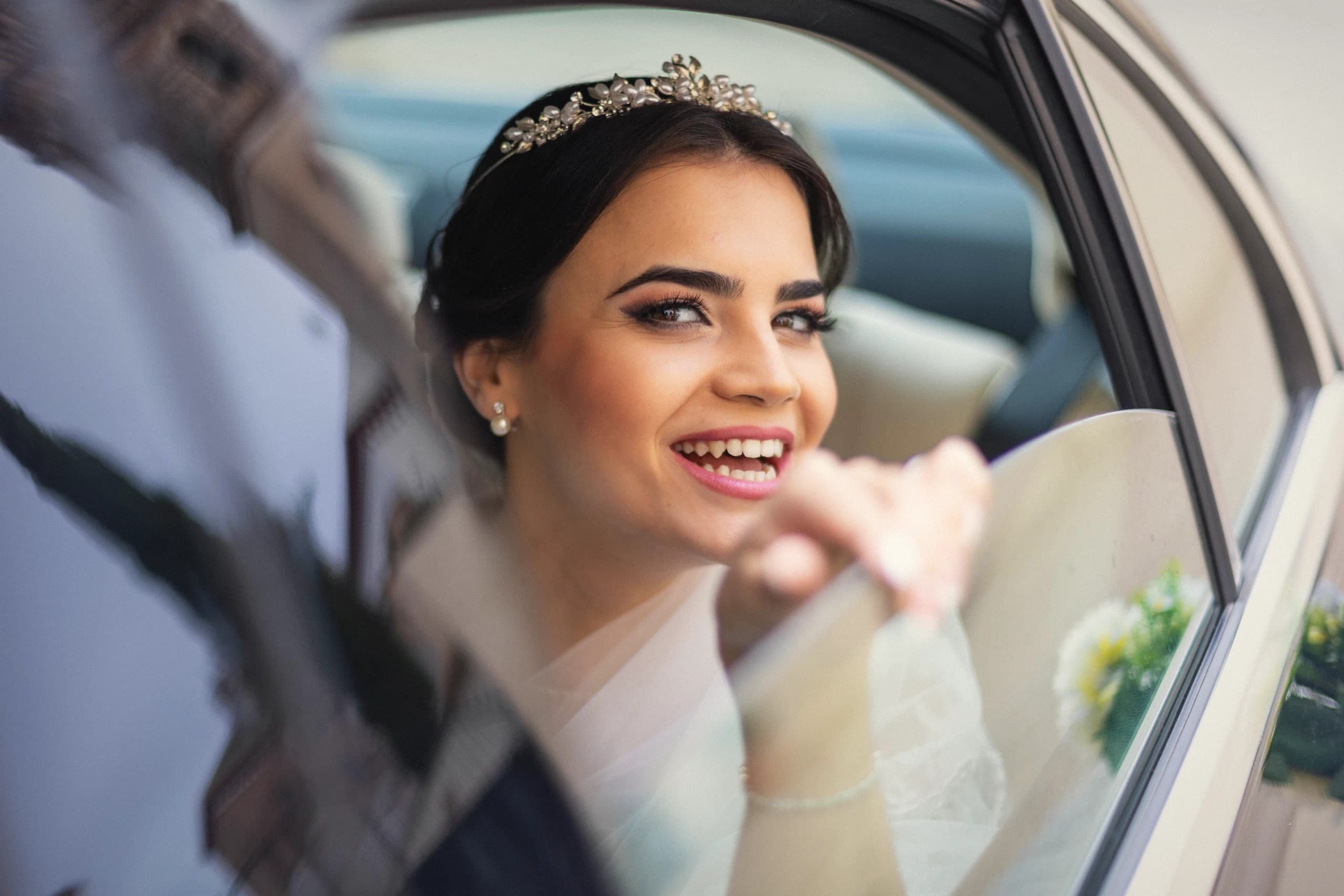La novia sonriendo desde la ventanilla del coche
