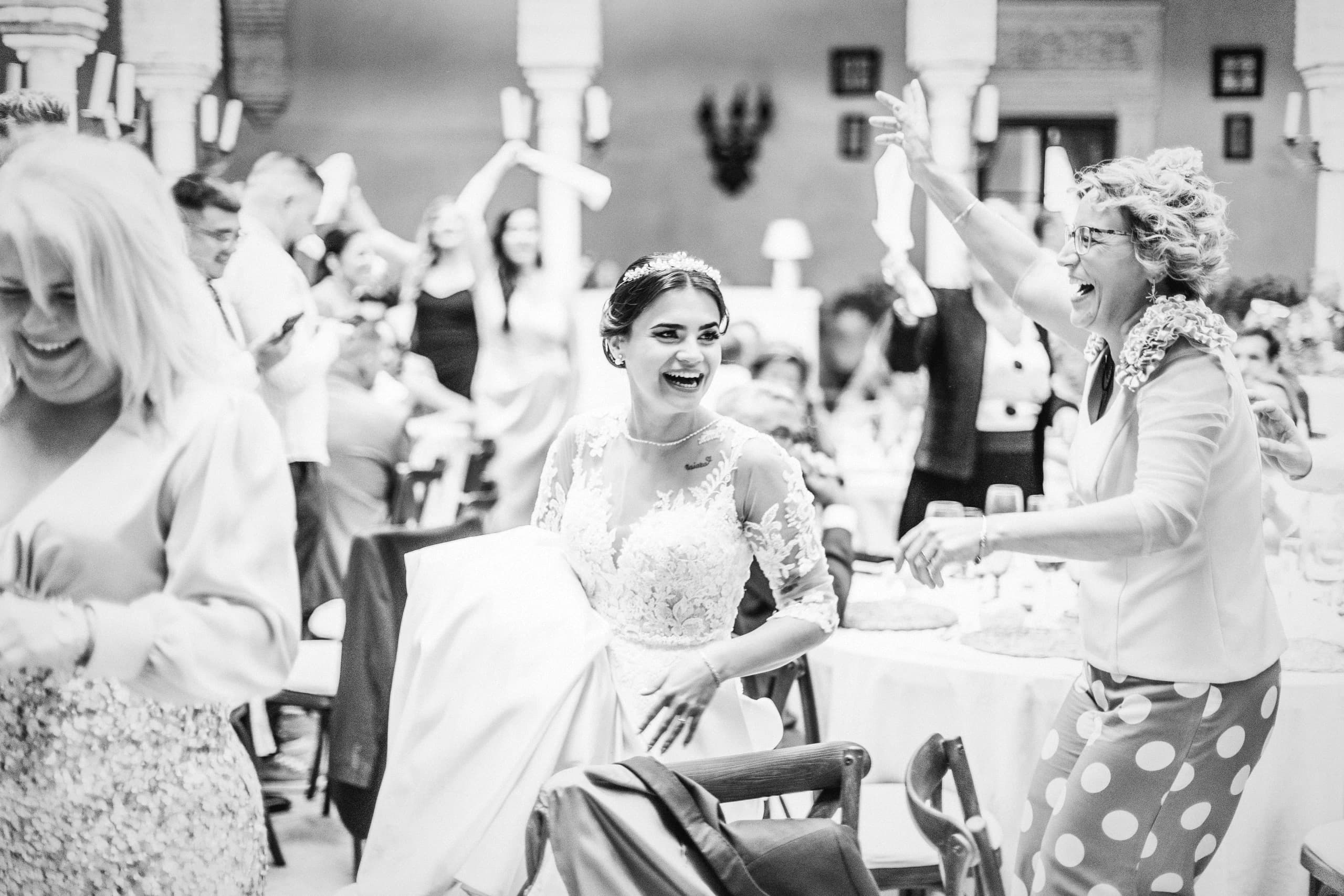 La novia riendo con las invitadas, en blanco y negro