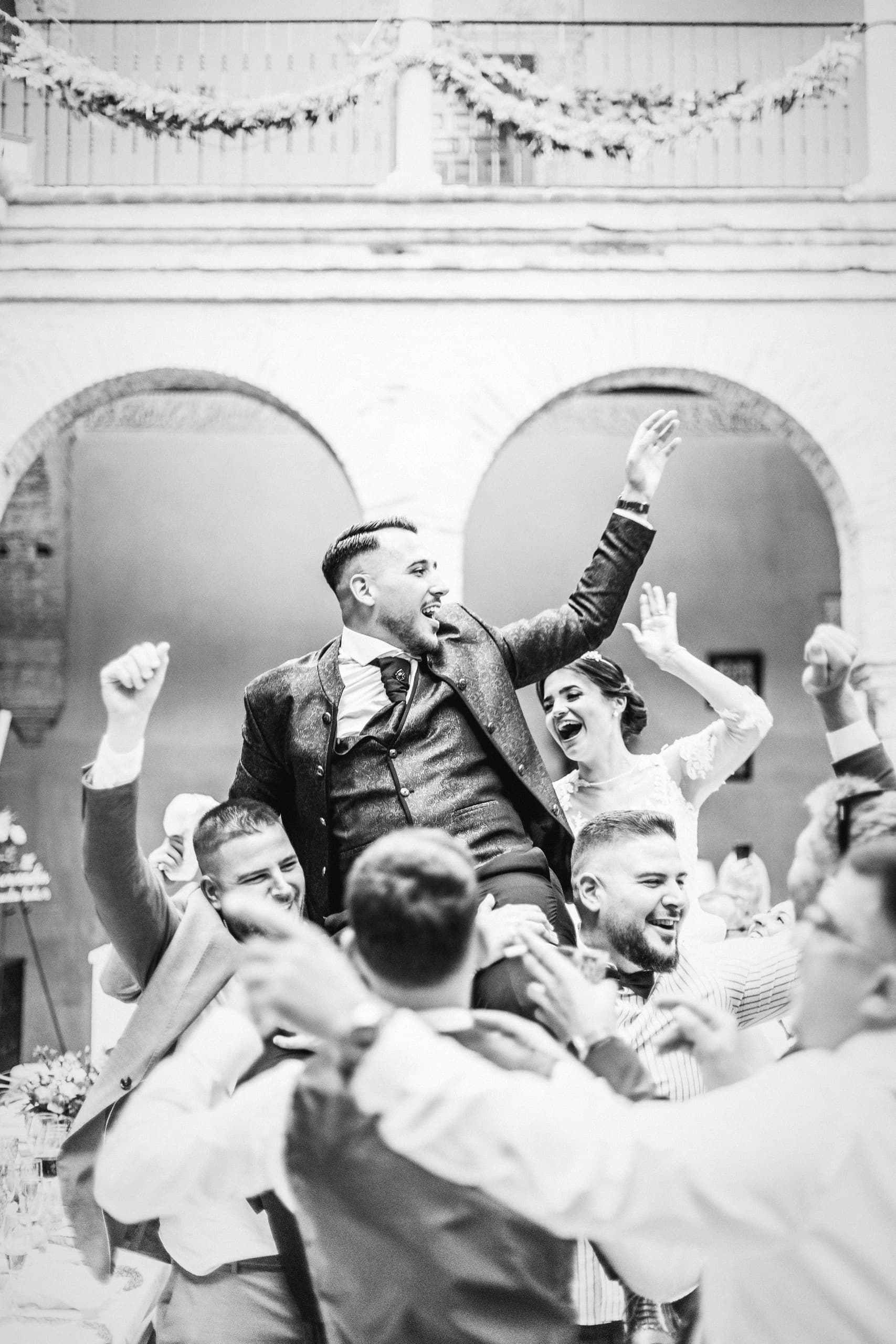 El novio a hombros de sus amigos en el patio, en blanco y negro