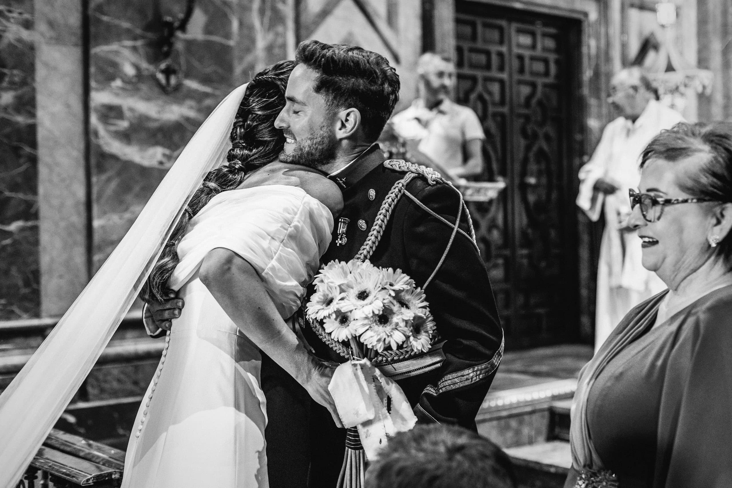 El abrazo del novio a la novia con el ramo entre los dos, en blanco y negro