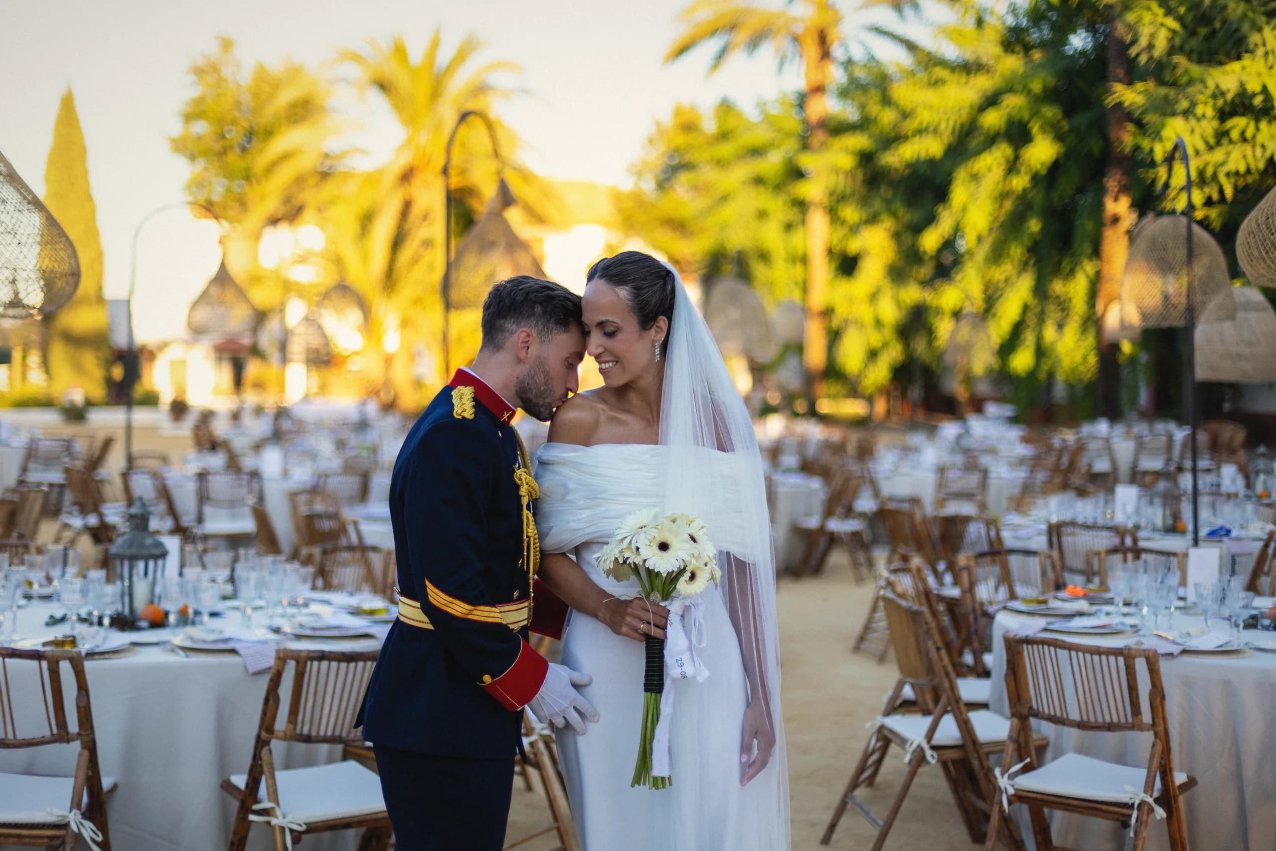 Los novios entre las mesas puestas, con las palmeras al fondo