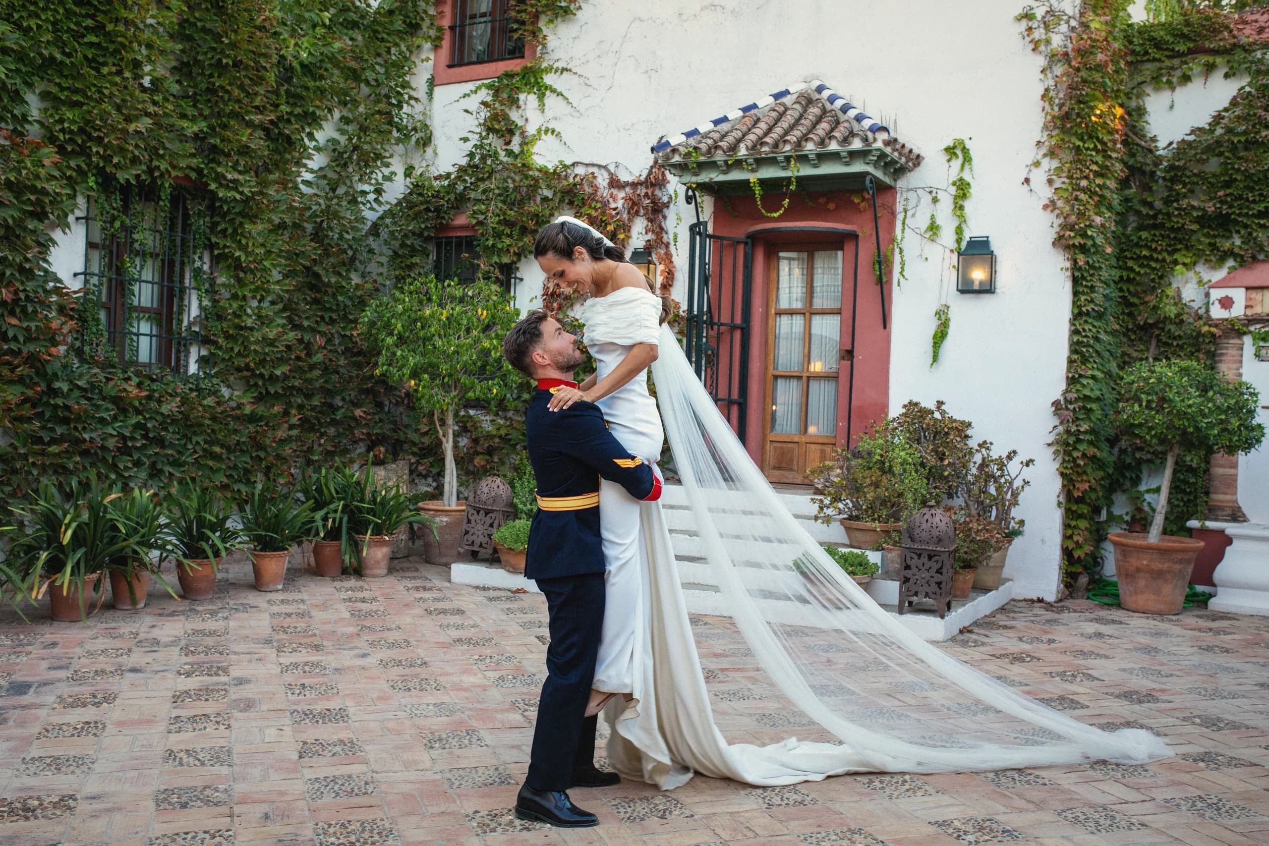 El novio levantando a la novia en el patio, con la cola del vestido extendida