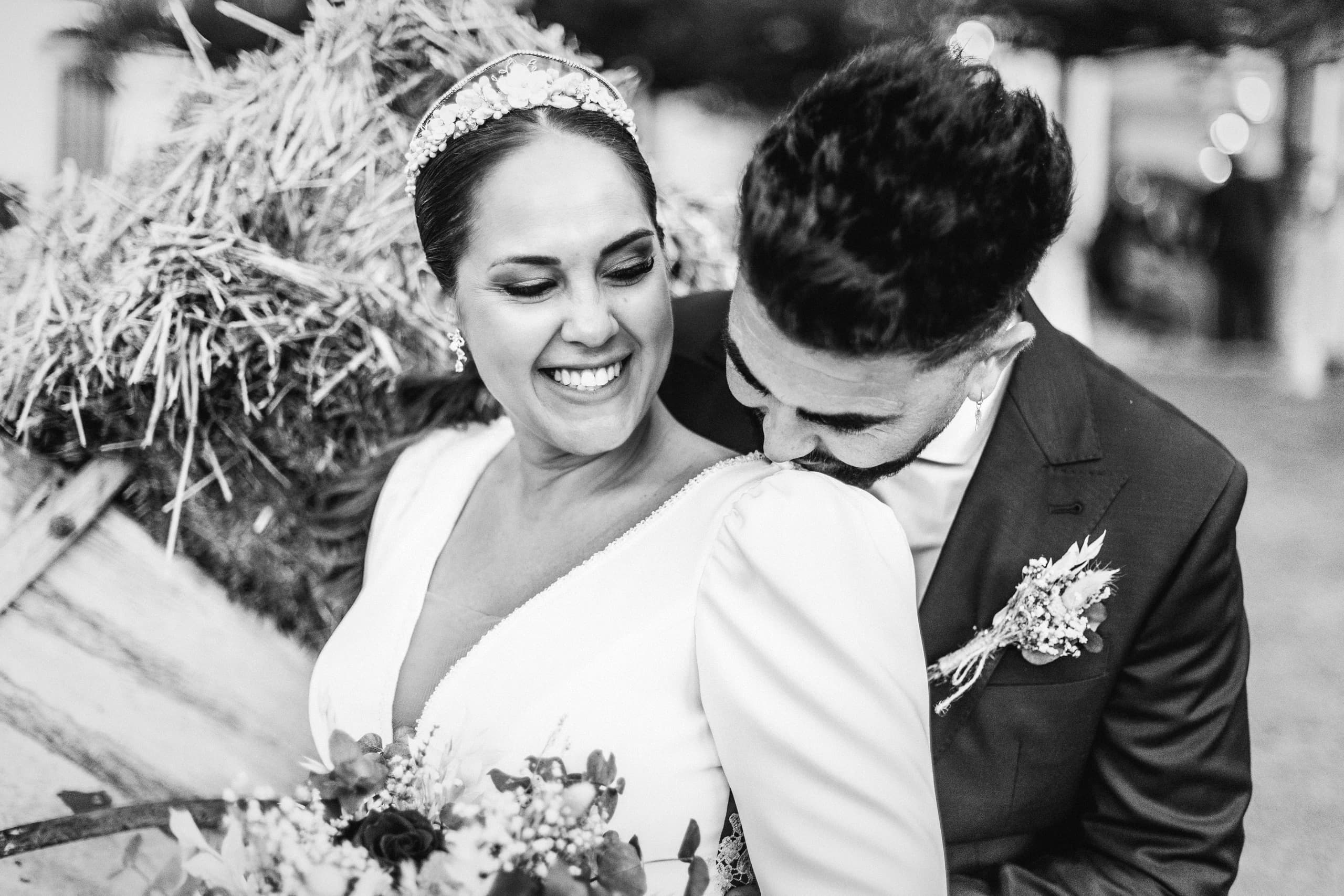 La novia riendo con el novio junto a las balas de paja, en blanco y negro