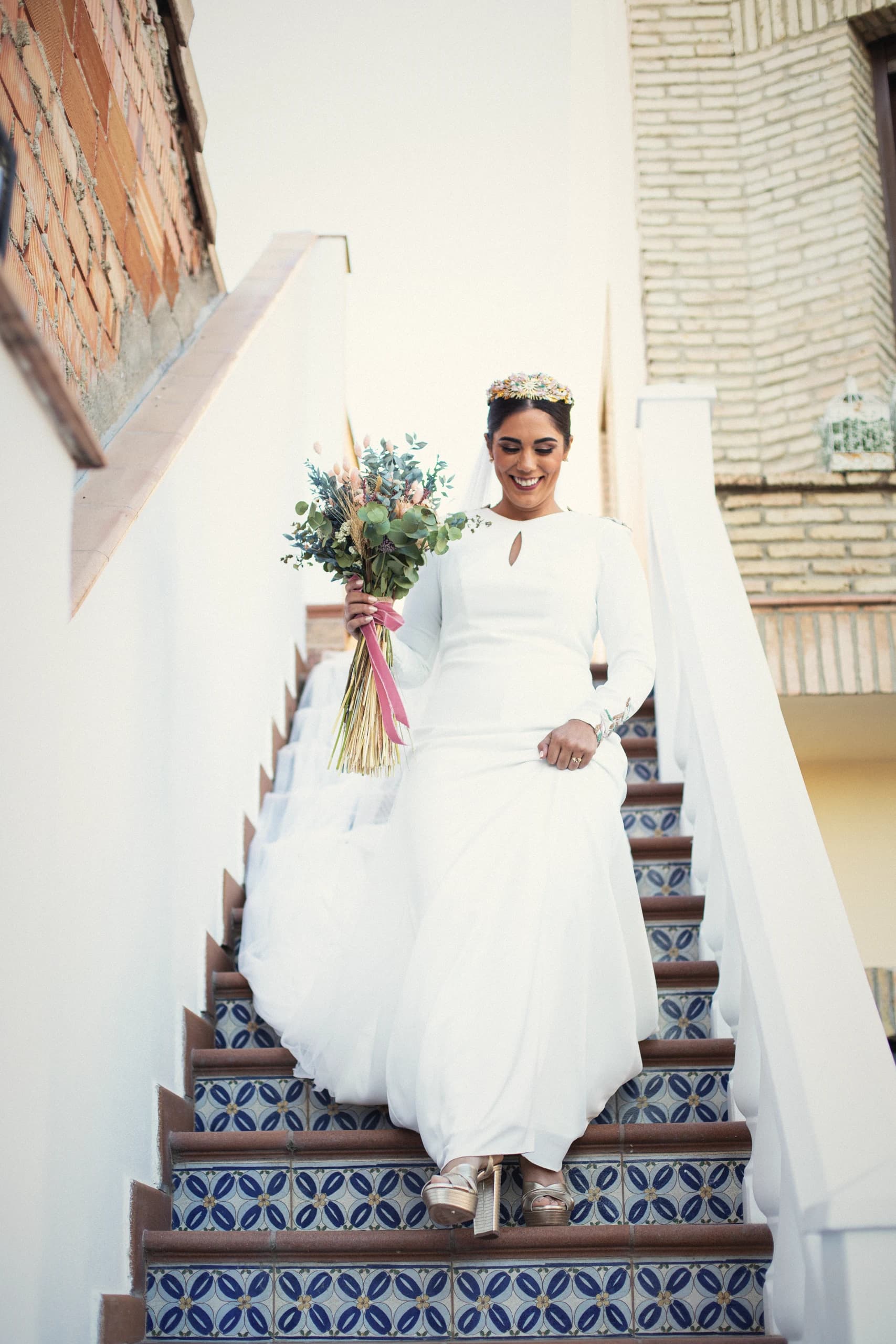 La novia bajando la escalera de azulejos con el ramo de colores