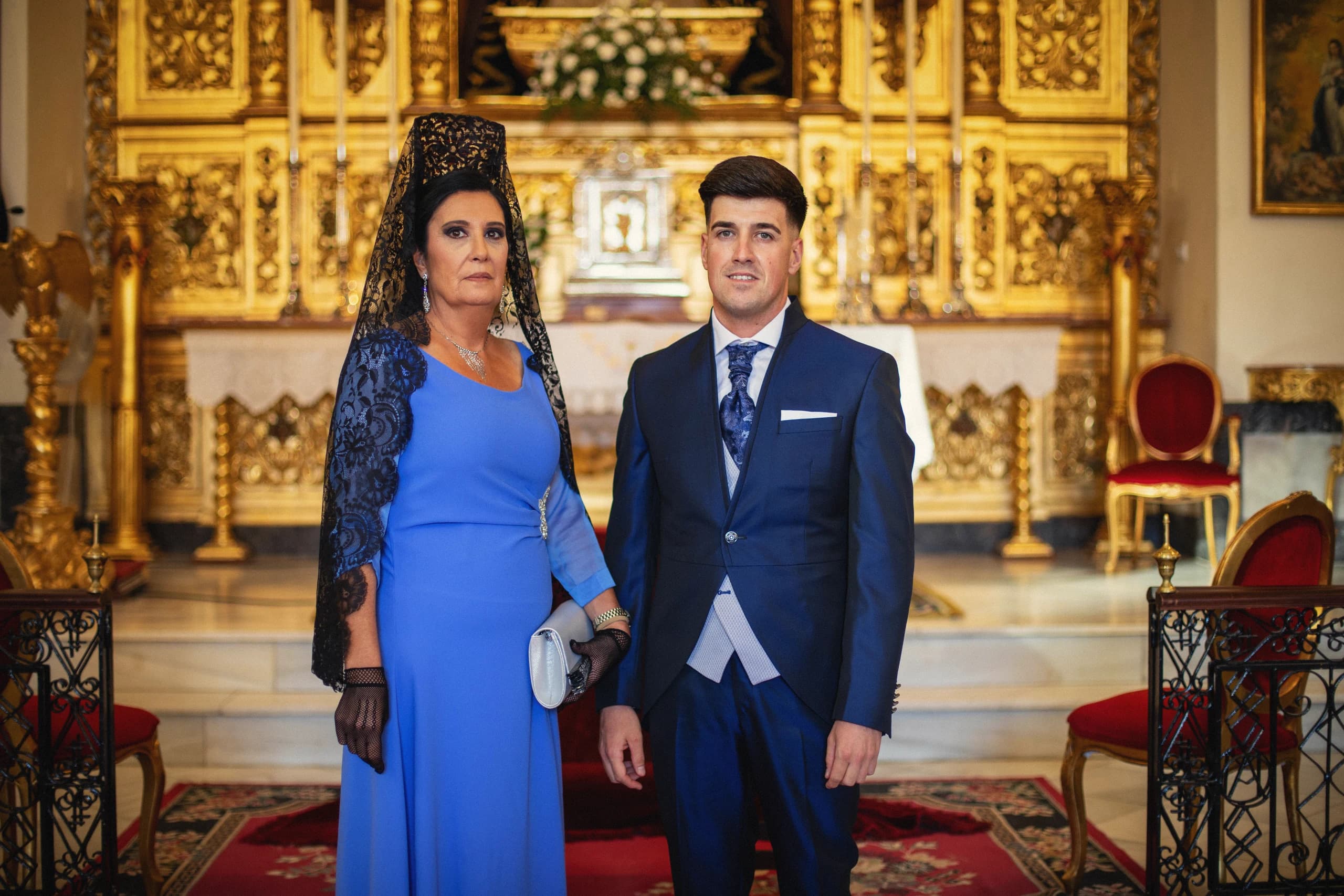 El novio con su madre de mantilla ante el retablo