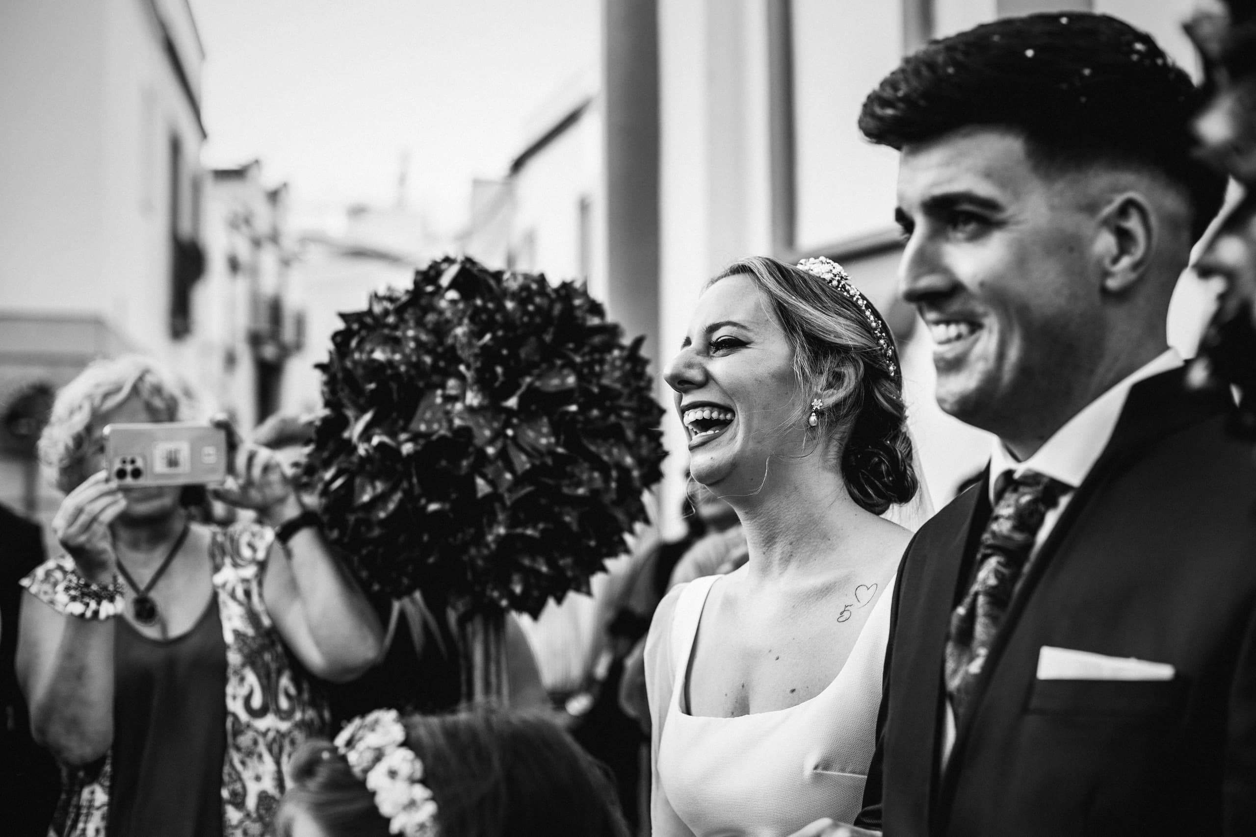 Los novios riendo a la salida, en blanco y negro