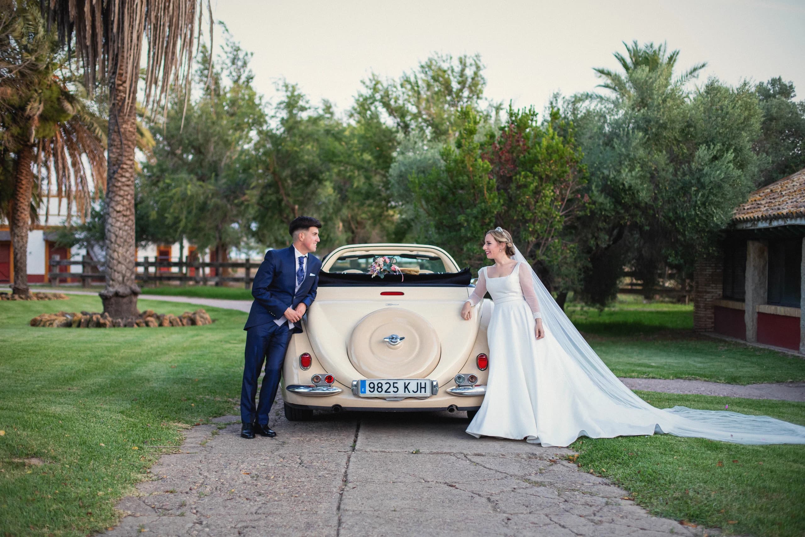 Los novios con el coche clásico entre palmeras