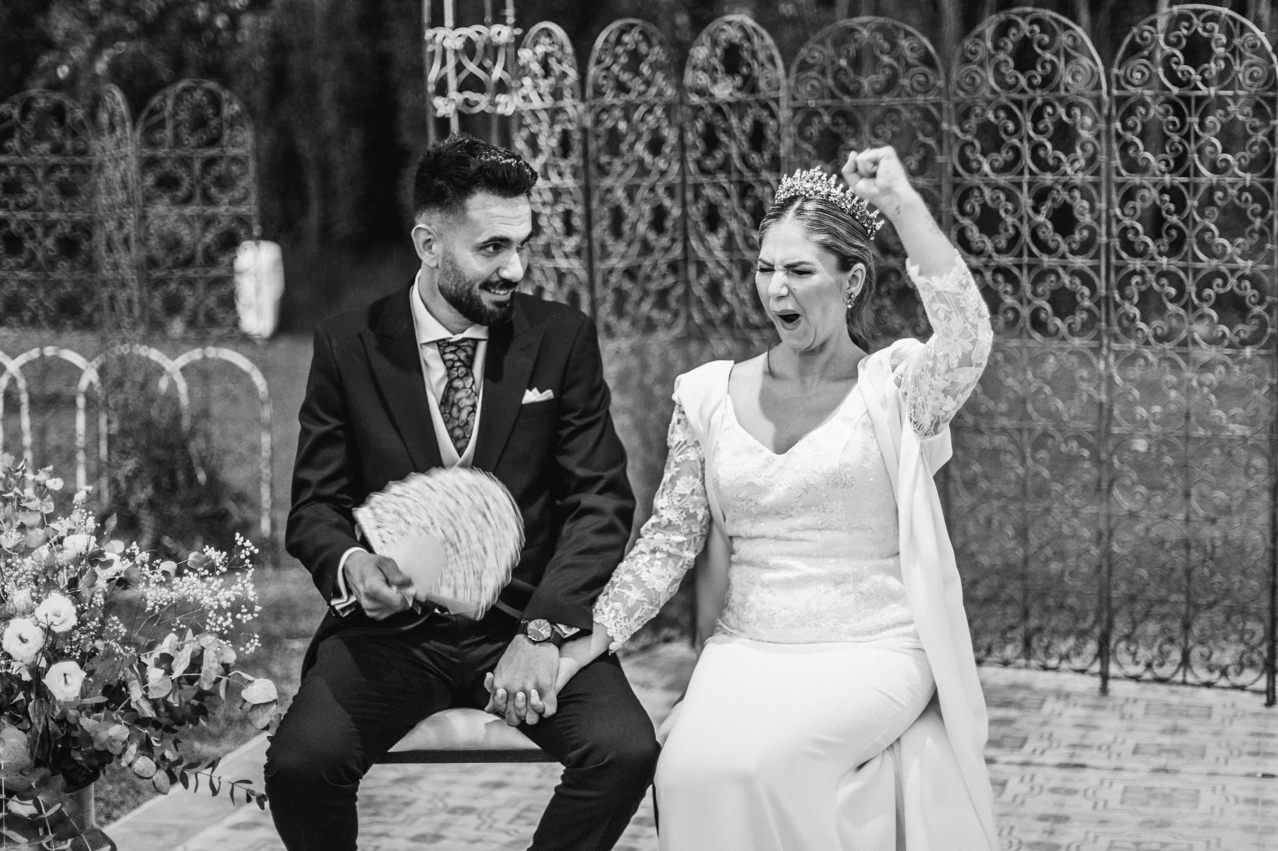 Los novios sentados ante la verja, con el abanico, en blanco y negro