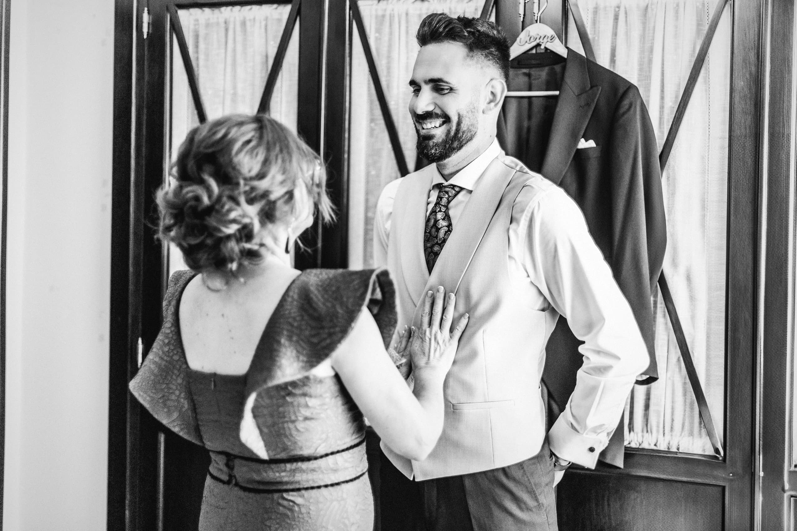 La madre del novio abrochándole la chaqueta, en blanco y negro