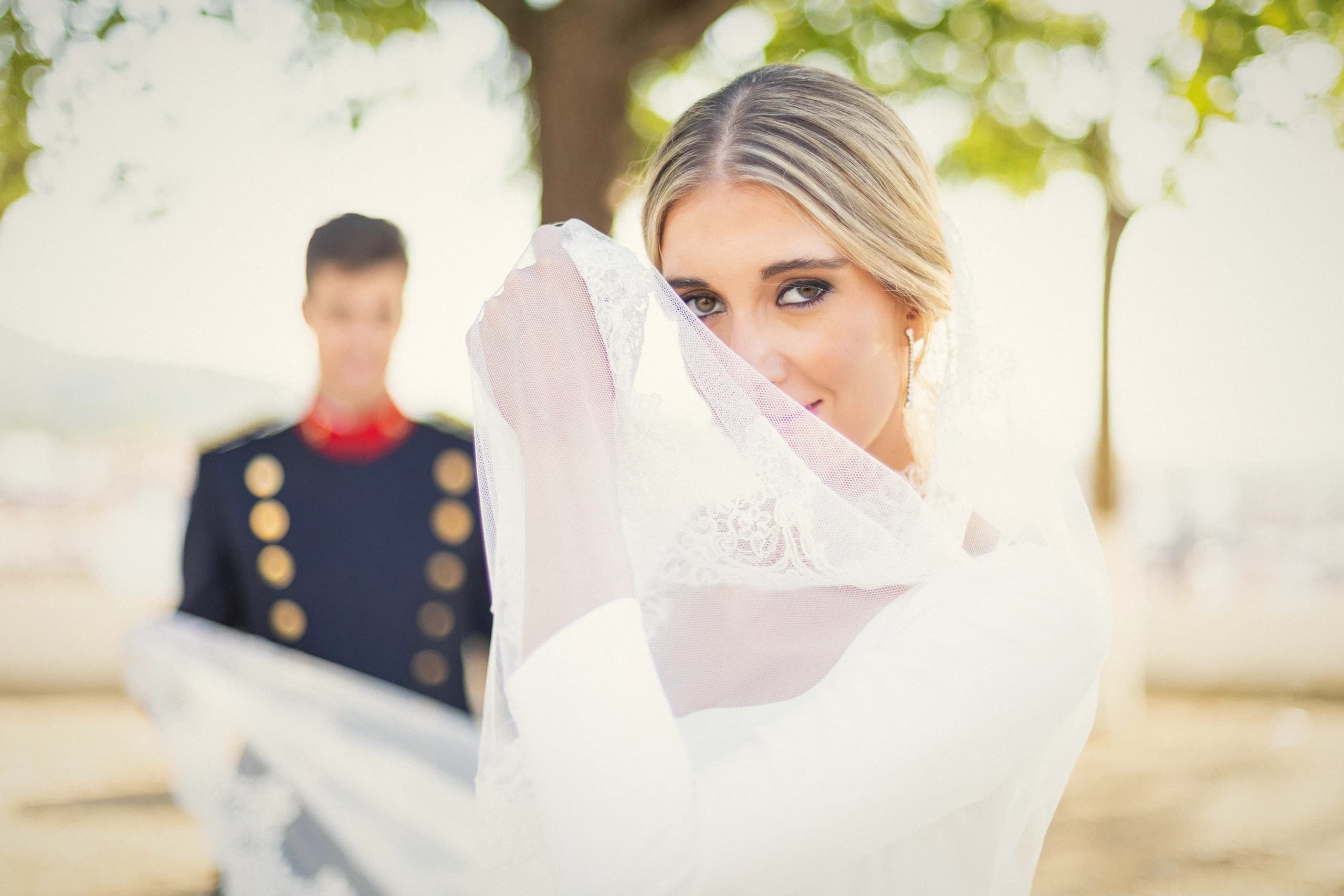 La novia jugando con el velo ante el novio de uniforme