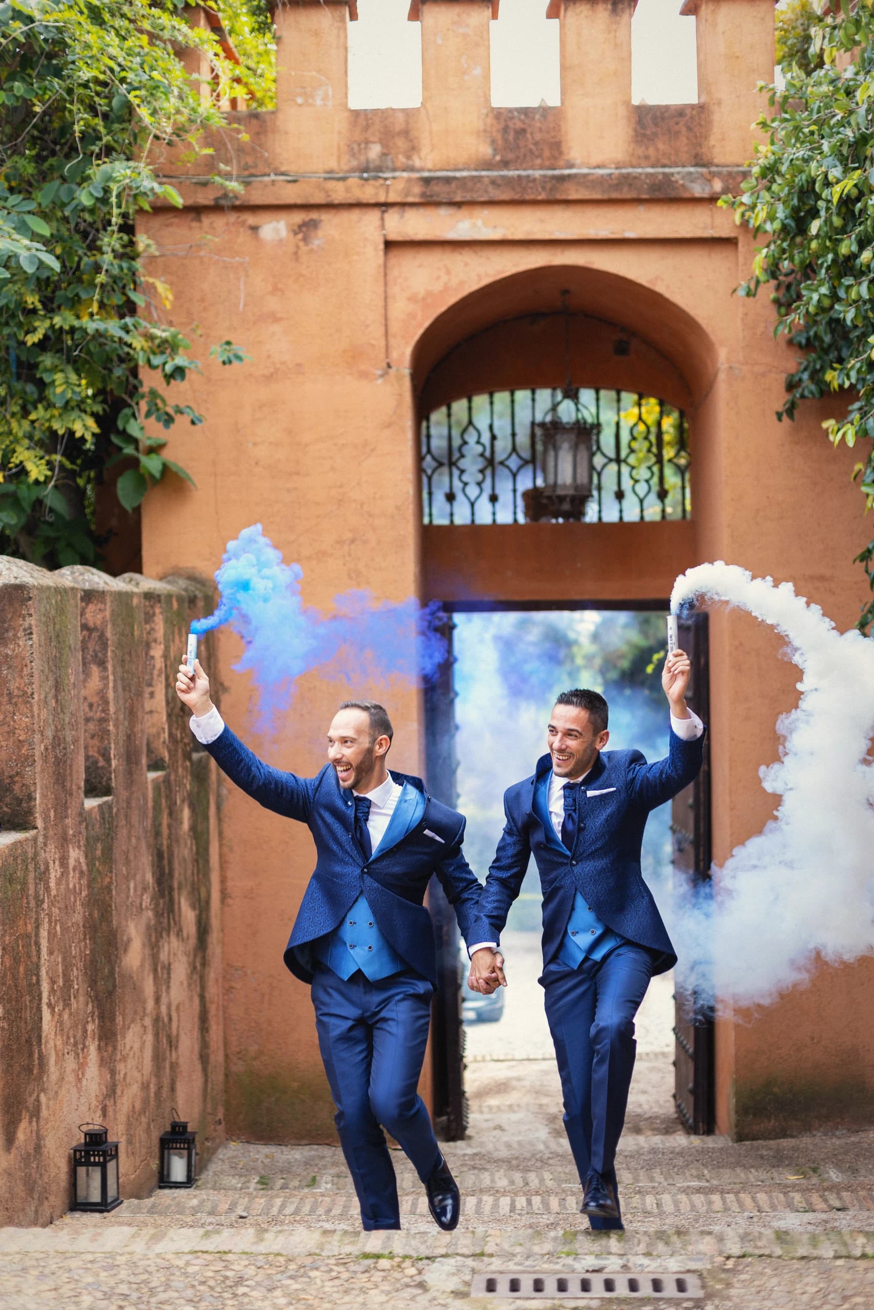 Los novios saliendo por el arco entre humo azul y blanco