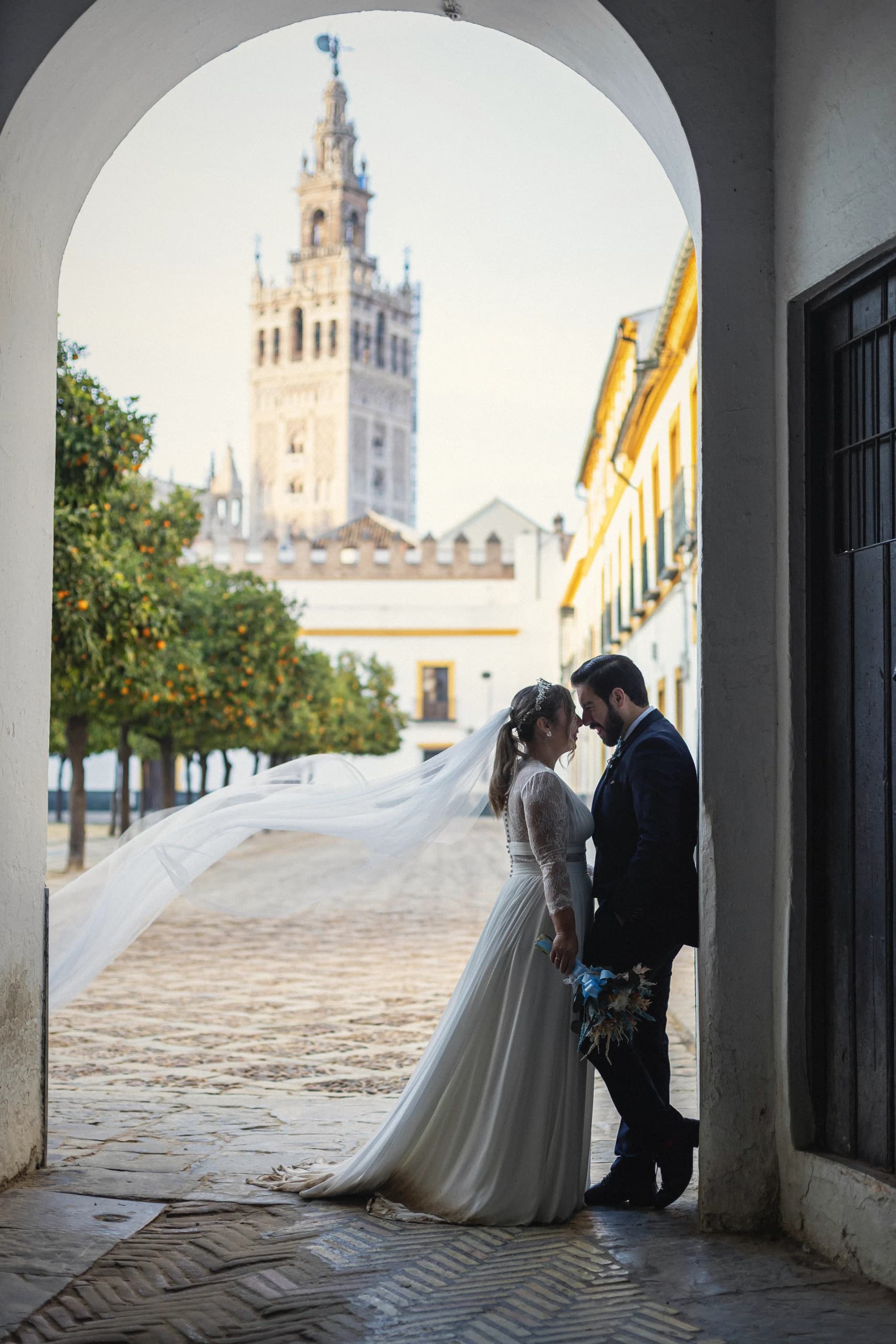 Los novios frente a frente bajo un arco con la Giralda al fondo