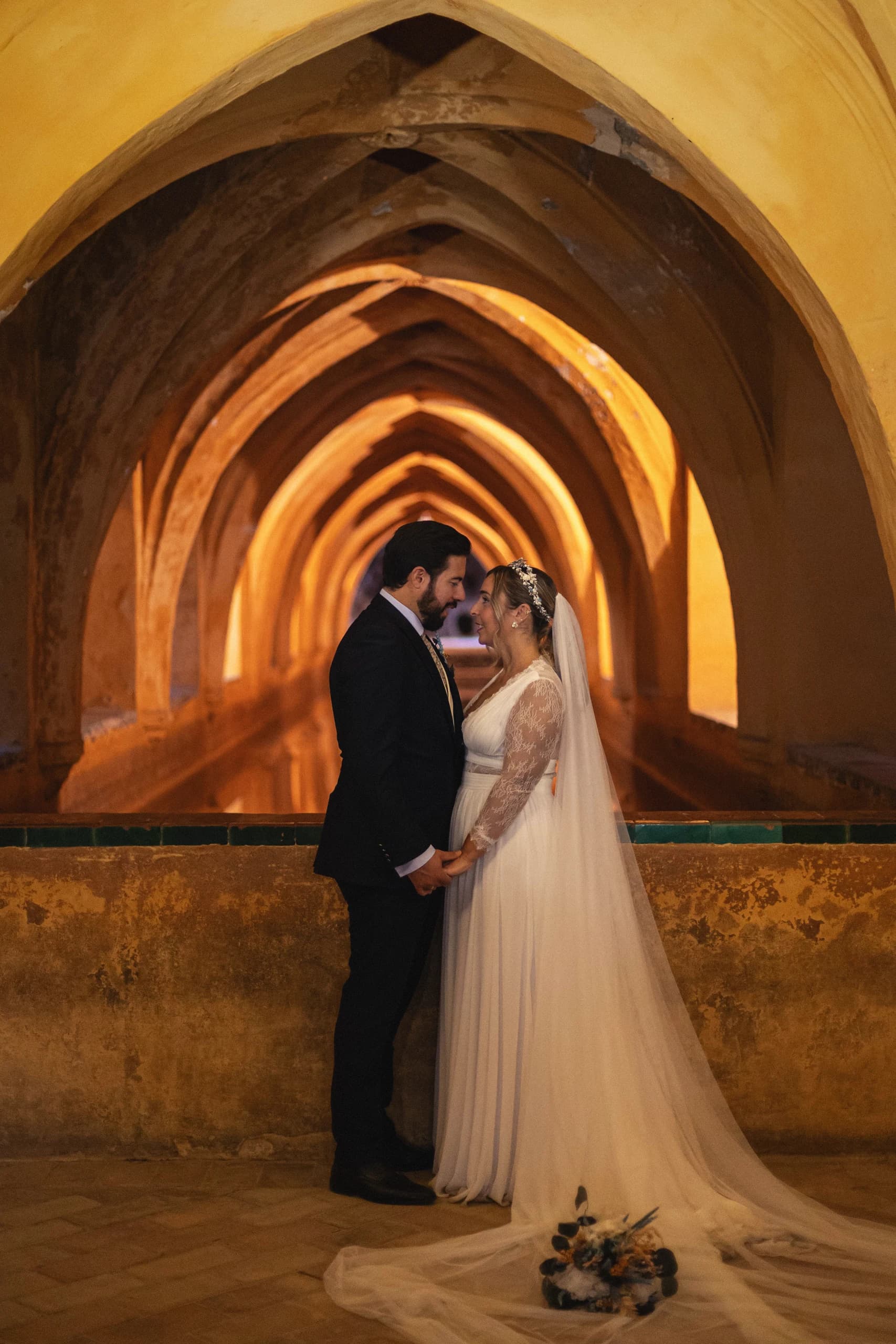 Los novios abrazados bajo los arcos dorados de los baños del Alcázar