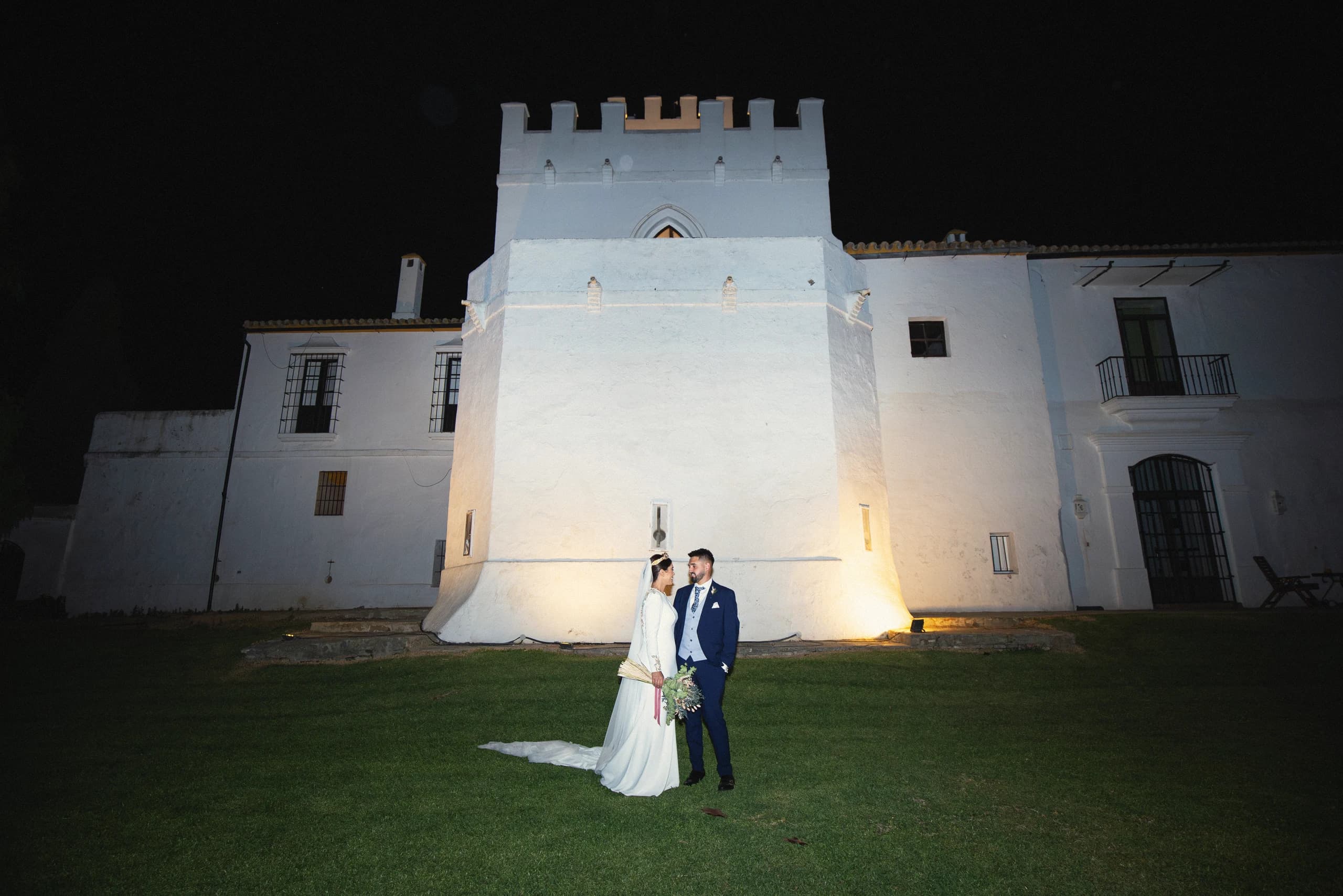 Los novios ante el cortijo blanco iluminado de noche