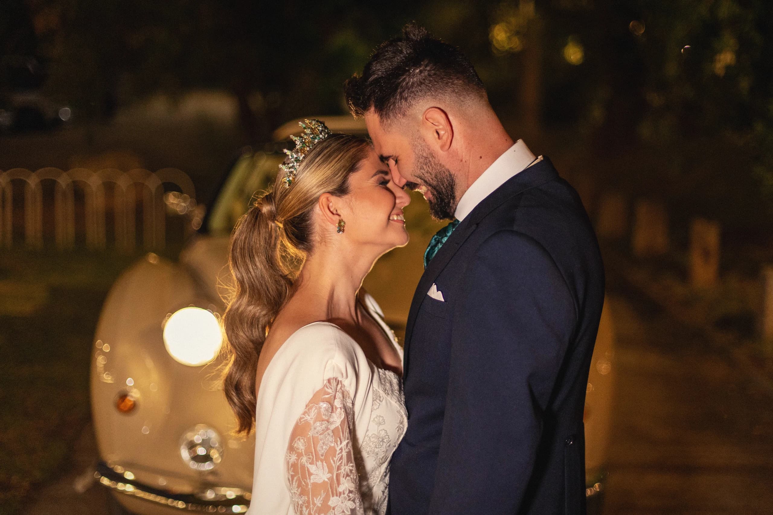 Los novios de noche frente a los faros del coche clásico